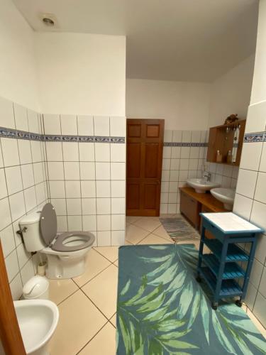 La salle de bains est pourvue de toilettes, d'un lavabo et d'un tabouret bleu. dans l'établissement La Maison Orange, à Moorea