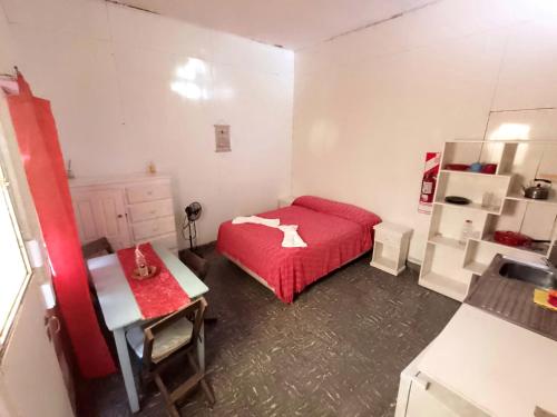 1 dormitorio con cama roja y lavamanos en Zafiro Departamentos en Capilla del Monte