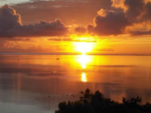 a sunset over a body of water with at Tehuarupe Surf Studio 2 in Haapiti