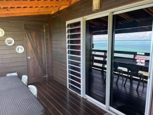 a screened in porch with a table and a piano at Tehuarupe Surf Studio 2 in Haapiti