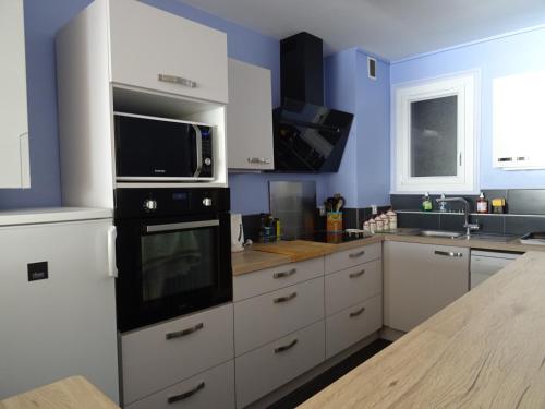 La cuisine est équipée de placards blancs et d'un four micro-ondes noir. dans l'établissement Appartement T3 vue sur mer, proche plage - FR-1-92-878, à Les Sables-dʼOlonne