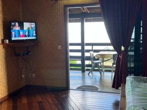 a living room with a sliding glass door with a television at Tehuarupe Surf Studios in Haapiti