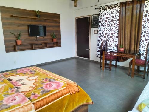 a room with a bed and a table and a tv at Samith Home Stay in Madikeri