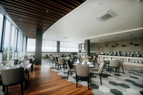 uma sala de jantar com mesas, cadeiras e janelas em Rogers Hotel Manado em Pineleng