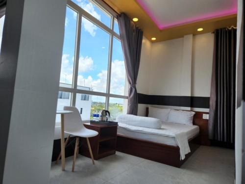 1 dormitorio con cama, escritorio y ventana en Khách sạn Vân Nhi, en Bạc Liêu