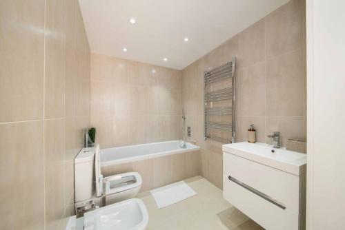 a bathroom with a sink and a toilet and a tub at 7 Borough Apartments - Spacious 2-Bed, 2-Bath in Prime Location in London