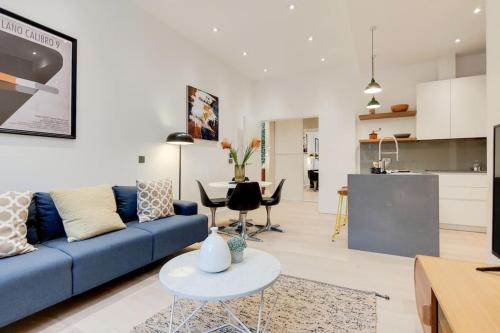 a living room with a blue couch and a table at 9 Borough Apartments - Spacious 2-Bed, 2-Bath Steps from London Bridge in London