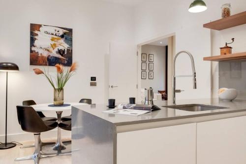 a kitchen with a sink and a table with chairs at 9 Borough Apartments - Spacious 2-Bed, 2-Bath Steps from London Bridge in London