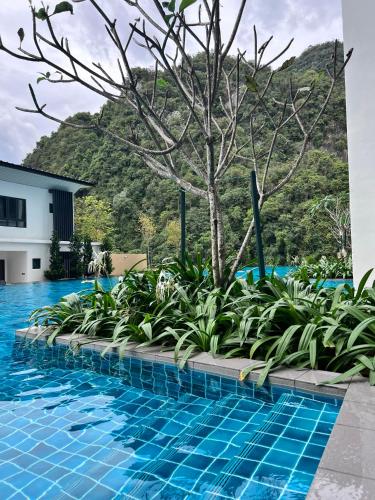 a resort swimming pool with a tree and a mountain in the background at Ojies Onsen - 3 guest only in Ipoh