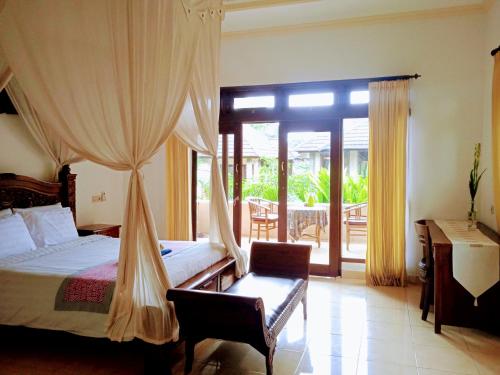 a bedroom with a bed and a desk and a window at Tanah Semujan Ubud in Ubud