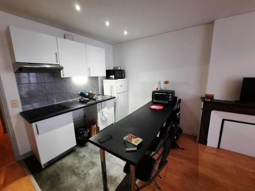 une cuisine avec une table et un comptoir noir dans l'établissement Charmant T2 au cœur de Bayonne, proche commodités - FR-1-239-891, à Bayonne