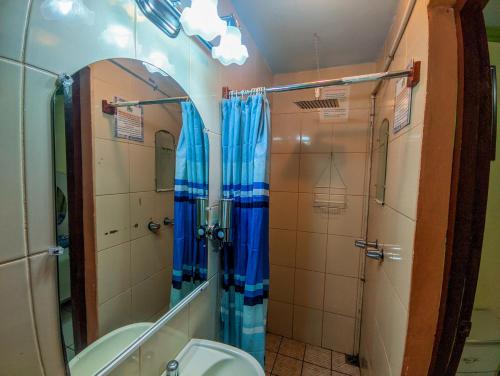 a bathroom with a shower and a toilet and a mirror at Hotel Fuente de Paz Managua in Managua