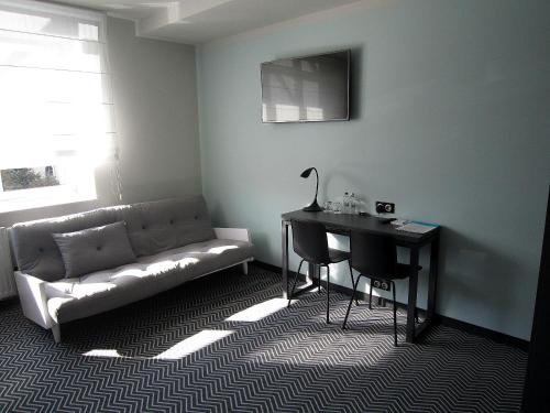 a living room with a couch and a table and a desk at So Stay Hotel in Gdańsk