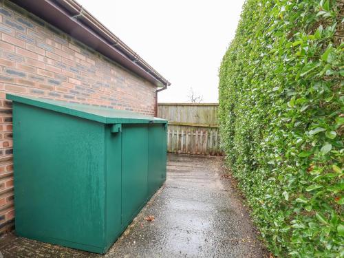 a green dumpster sitting next to a brick wall at 4 Green Farm Cottage in Chester