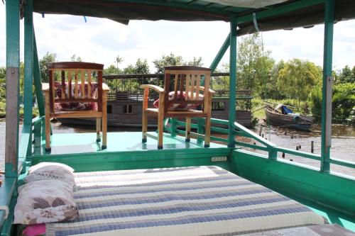 duas cadeiras e uma cama na parte de trás de um barco em Orangutan Kelotok Houseboat for 6 person em Pangkalan Bun