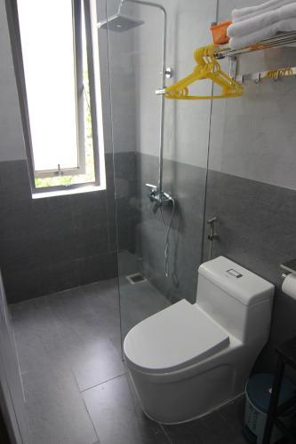 La salle de bains est pourvue de toilettes et d'une douche en verre. dans l'établissement Dory Homestay, à Hue