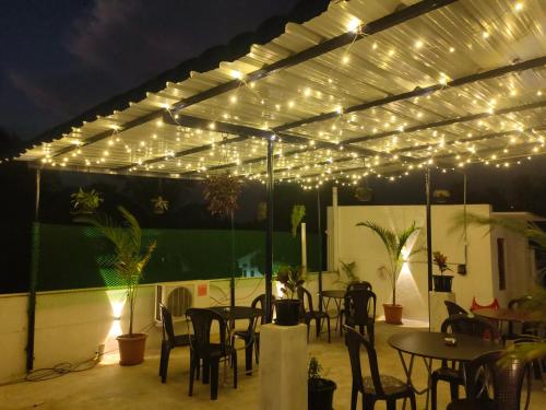 um pátio com mesas, cadeiras e luzes em La Township Residency em Pondicherry