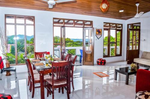 una sala da pranzo con tavolo, sedie e finestre di SaRu Holiday Apartment - Upto 6 Guests a Kandy