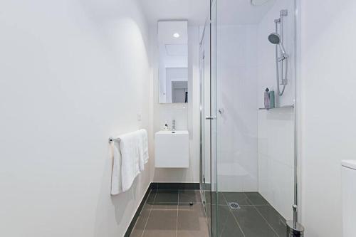 uma casa de banho com uma cabina de duche em vidro e um lavatório. em Chic Urban Oasis em Melbourne
