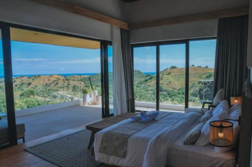a bedroom with a large bed and large windows at Truntum Boutique Mandalika in Kuta Lombok