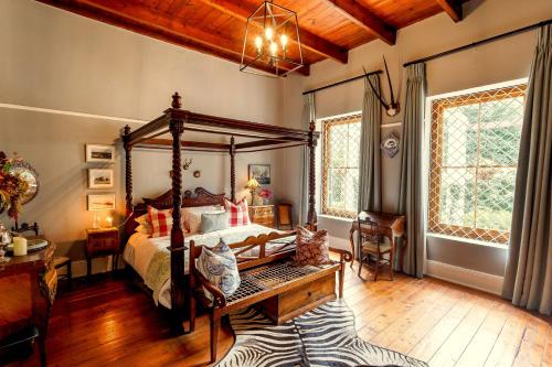 een slaapkamer met een hemelbed en een houten vloer bij Oude Pastorie in Nieu-Bethesda