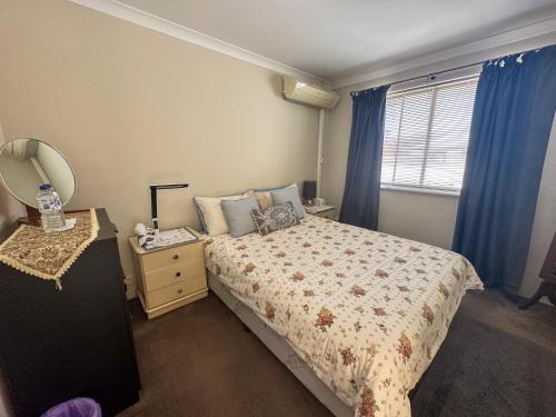 een slaapkamer met een bed, een spiegel en een raam bij Joondalup Guest House in Perth