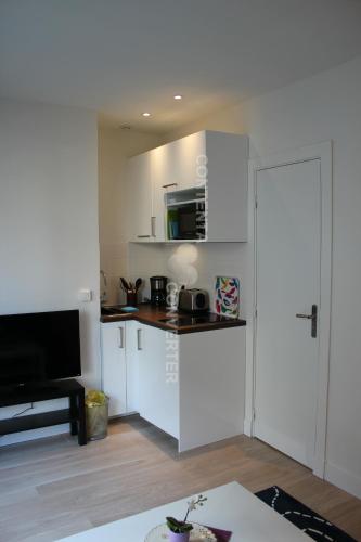 Elle comprend une petite cuisine avec des placards blancs et une porte. dans l'établissement Tour Eiffel Grenelle, à Paris