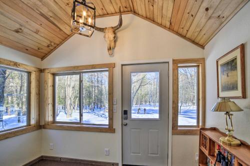 Cette chambre dispose de fenêtres et d'une porte avec une tête de cerf sur le mur. dans l'établissement Peaceful Marquette Cottage with Sunroom!, à Marquette