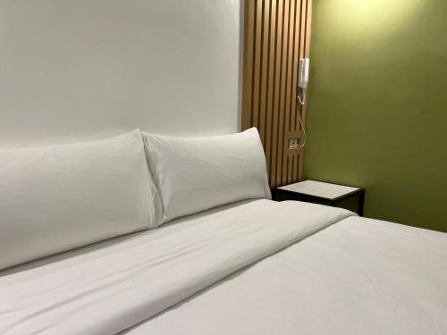 a bed with white sheets and pillows in a room at Damara Hotel at Ciudad Elmina in Dagupan