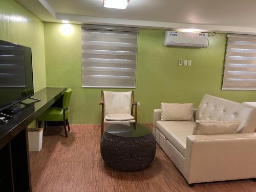a living room with a couch and a desk and a tv at Damara Hotel at Ciudad Elmina in Dagupan