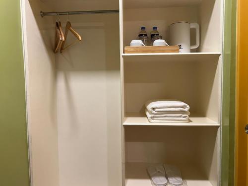 a closet with white shelves and towels in it at Damara Hotel at Ciudad Elmina in Dagupan
