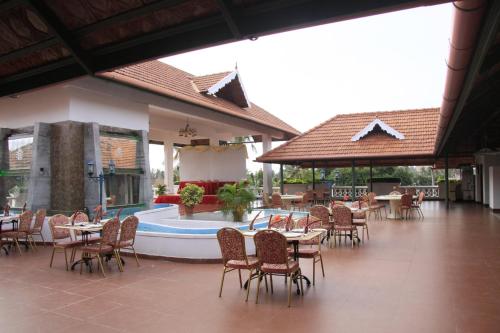 ein Restaurant mit Tischen und Stühlen sowie einem Pool in der Unterkunft Hotel Rajadhani in Thiruvananthapuram