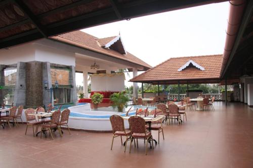 a restaurant with tables and chairs and a swimming pool at Hotel Rajadhani in Trivandrum