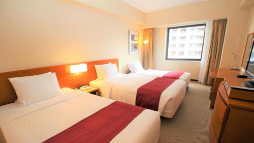 a hotel room with two beds and a television at ANA Holiday Inn Sendai by IHG in Sendai