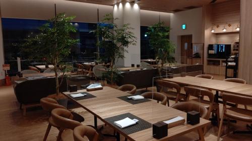 a restaurant with wooden tables and chairs and plants at ANA Holiday Inn Sendai by IHG in Sendai
