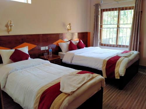 a hotel room with two beds and a window at HOTEL CROWN HORIZON in Sauraha