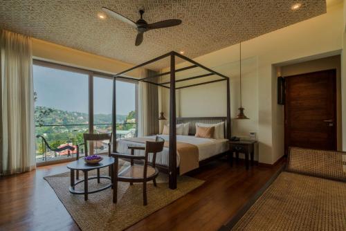 ein Schlafzimmer mit einem Himmelbett sowie einem Tisch und Stühlen in der Unterkunft Rivora Heights in Kandy