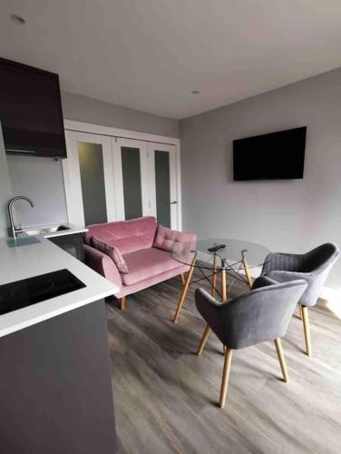 ein Wohnzimmer mit einem rosa Sofa und Stühlen in der Unterkunft Boutique Annexe Close To Norwich City & Airport in Horsham St Faith