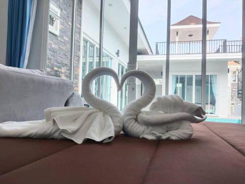 deux cygnes de serviettes assises sur le sol dans un salon dans l'établissement Aranya pool villa, à Ban Phu Yai