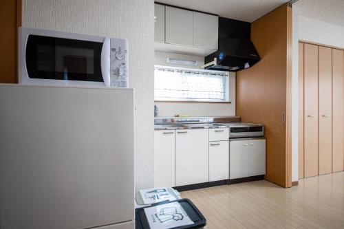 a kitchen with white cabinets and a scale in a room at Sumiyoshi House Room B in Otaru