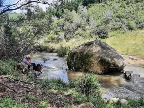 two people are standing in a river with a rock at Diamond Vault Rustic Mountain Cabins in Hogsback