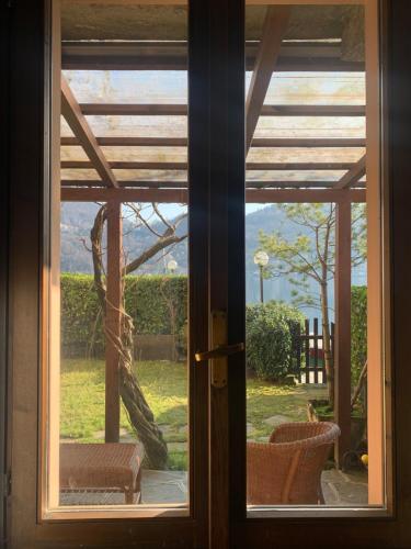 a door with a window looking out at a yard at Villa Giardino con pontile sul Lago D’Orta in riva in Orta San Giulio