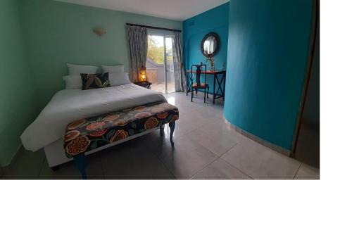 a bedroom with a bed and a blue wall at Queenz Bed & Breakfast in Durban