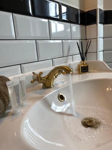 ein weißes Waschbecken mit einem goldenen Wasserhahn im Bad in der Unterkunft Villa La Dune - Ontbijt & parking inclusief in Middelkerke