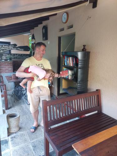 a man holding a baby in his arms next to a bench at Mama Villa Hikkaduwa in Hikkaduwa