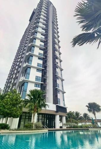 a tall building with a swimming pool in front of it at Almas Suites Muji 100mbps Netflix By STAY in Nusajaya