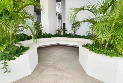 a garden with palm trees and a white bench at Almas Suites Muji 100mbps Netflix By STAY in Nusajaya