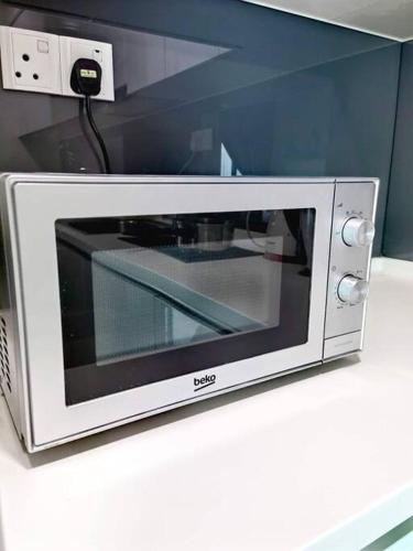 a microwave sitting on top of a counter at Almas Suites Muji 100mbps Netflix By STAY in Nusajaya
