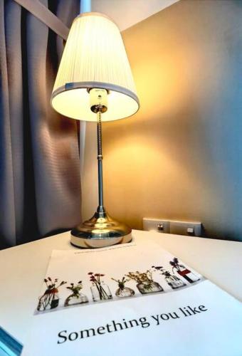 a lamp sitting on top of a table with a book at Almas Suites Muji 100mbps Netflix By STAY in Nusajaya