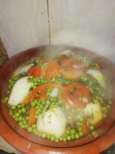 a plate of food with peas tomatoes and vegetables at Gite Oukaimeden in Oukkainrdem